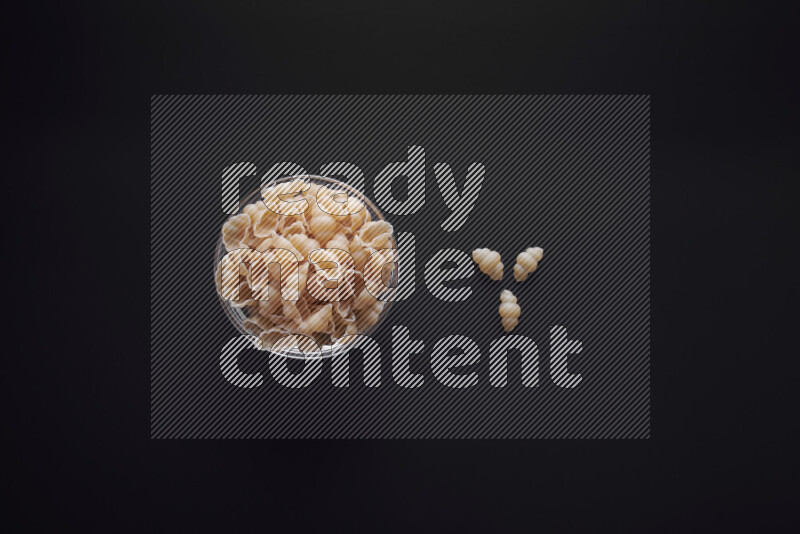 Snails pasta in a glass bowl on black background