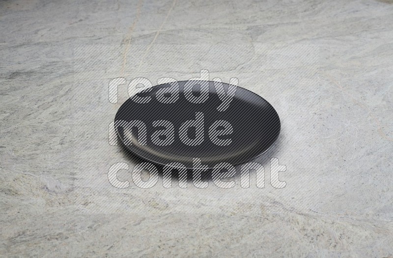 black ceramic circular plate on grey marble flooring.