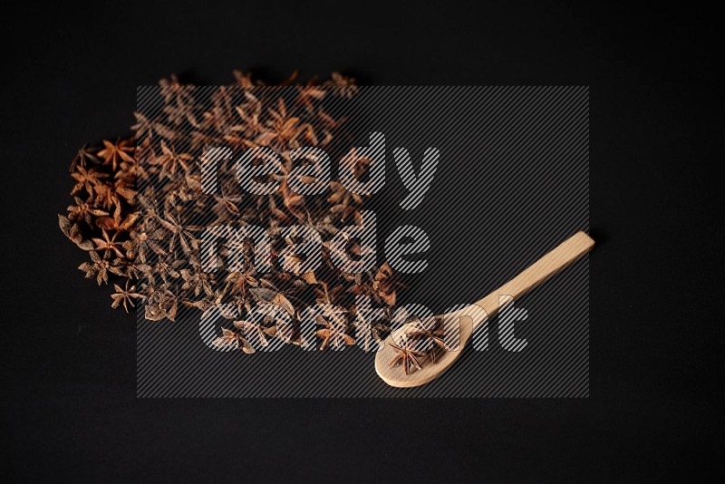 Star Anise in a wooden spoon and spreading on a black flooring