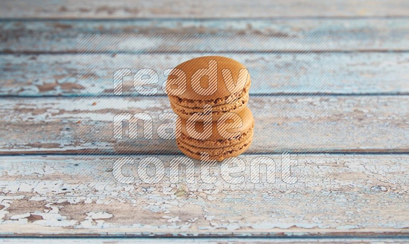 45º Shot of two Brown Maple Taffy macarons on light blue wooden background