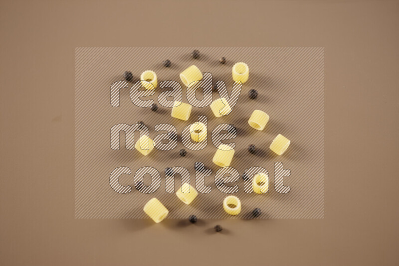 Raw pasta with different ingredients such as cherry tomatoes, garlic, onions, red chilis, black pepper, white pepper, bay laurel leaves, rosemary and cardamom on beige background