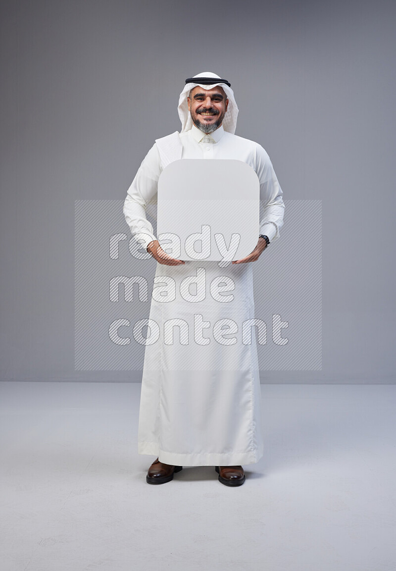 Saudi man Wearing Thob and white Shomag standing holding social media sign on Gray background