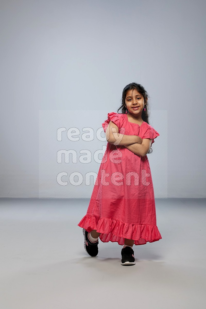 A girl standing interacting with the camera on gray background