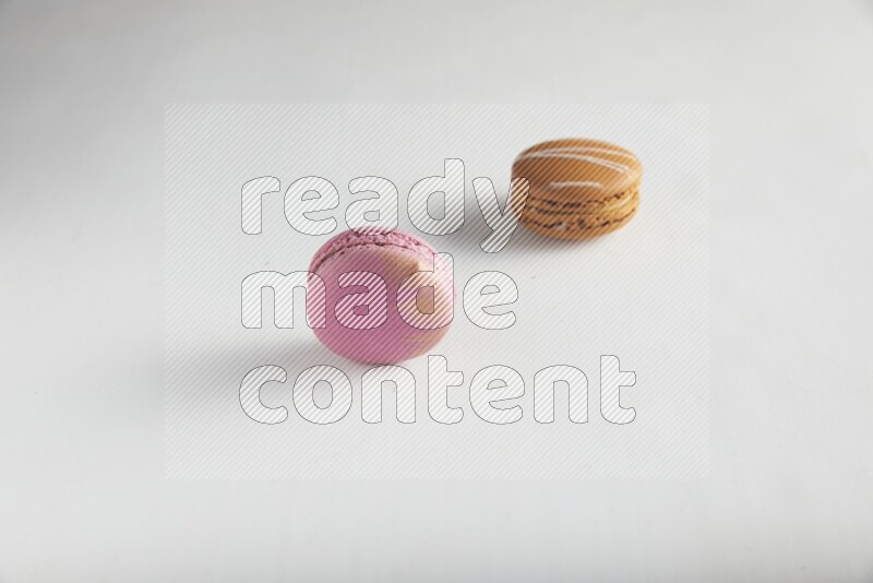 45º Shot of of two assorted Brown Irish Cream, and Purple Strawberry macarons on white background