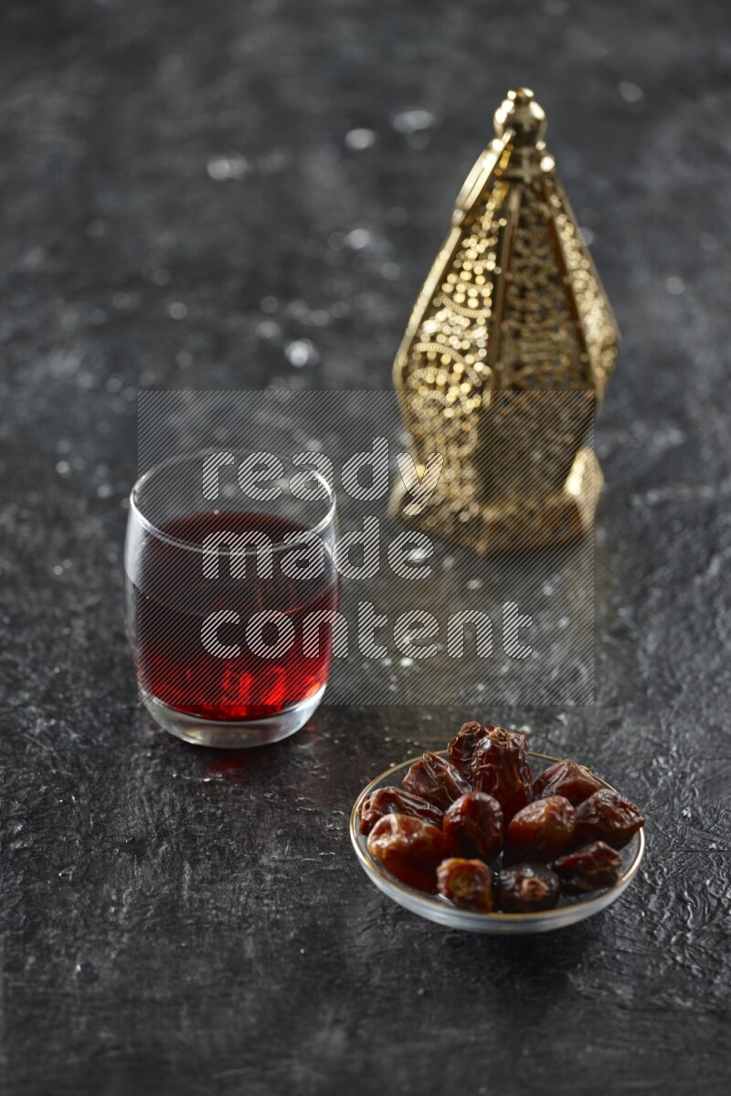 A golden lantern with different drinks, dates, nuts, prayer beads and quran on textured black background