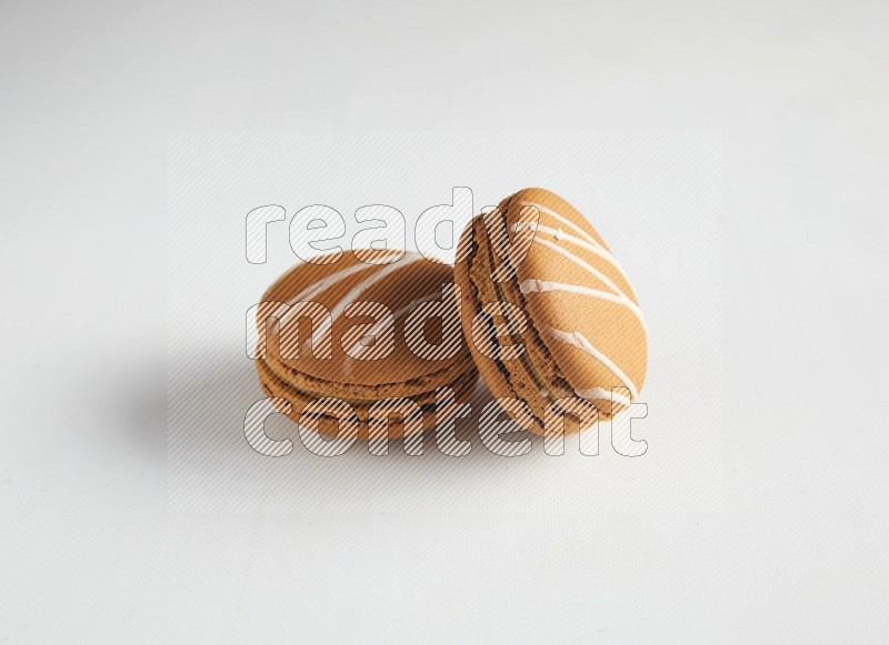 45º Shot of two Brown Irish Cream macarons on white background