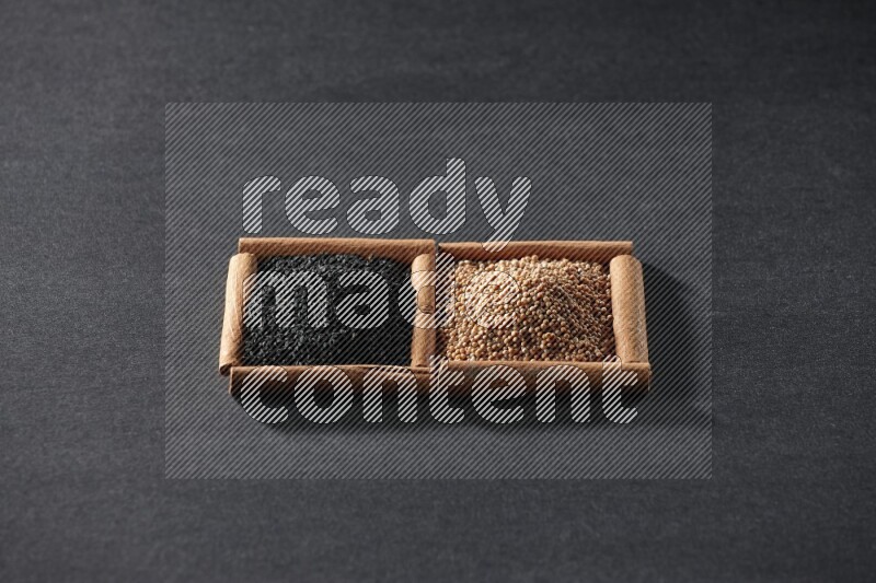 مربعان من أعواد القرفة ممتلئان بحبوب الخردل وحبة البركة السوداء علي خلفية سوداء