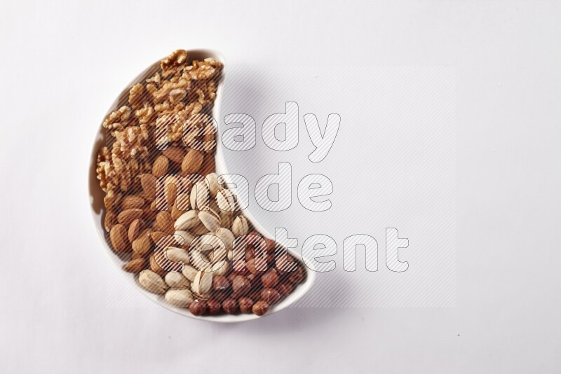 Mixed nuts in a crescent pottery plate on white background