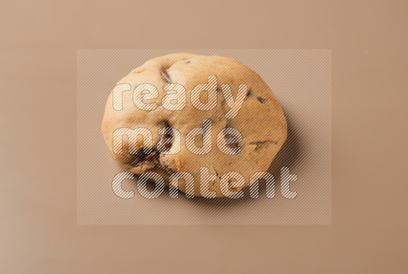 a whole chocolate chip cookie on a brown background