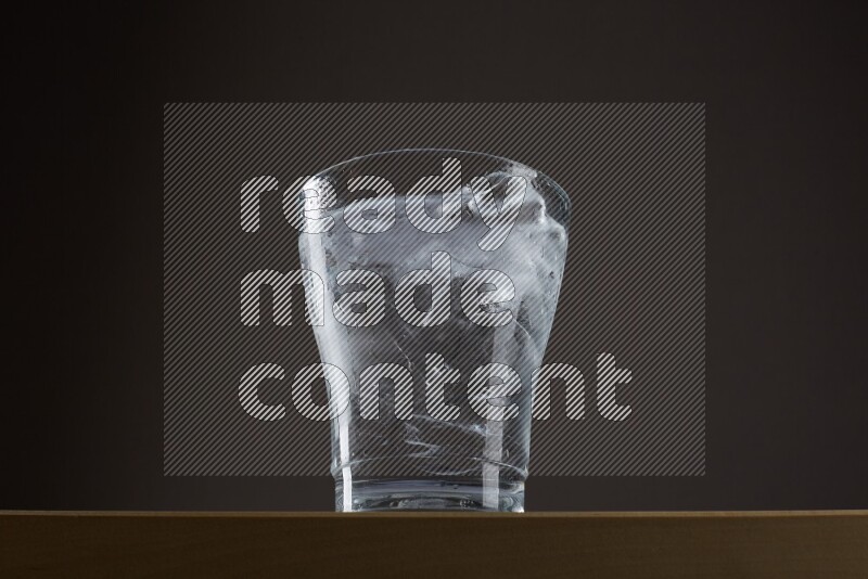 Low angle shot of a glass of water and ice on grey background