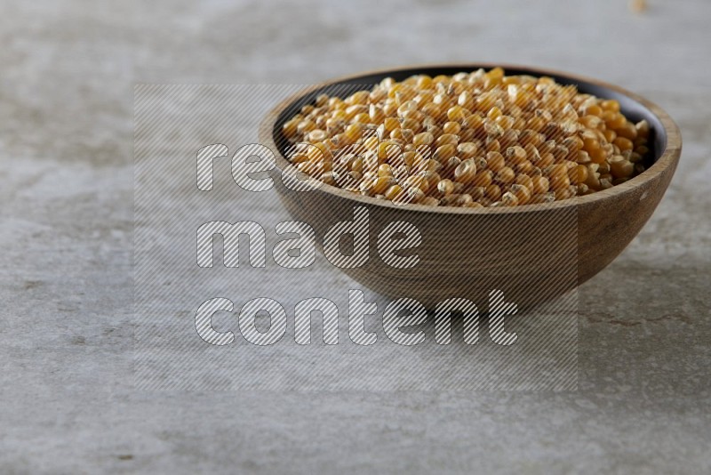 corn kernel in a wooden bowl on a grey textured countertop