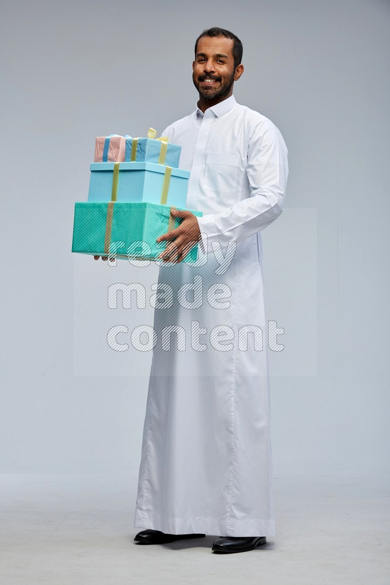 Saudi man Wearing thob standing holding gift box on Gray background