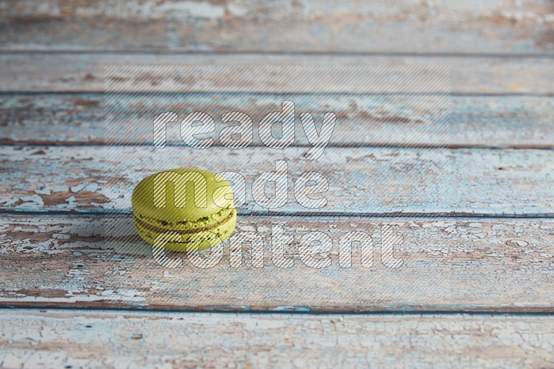 45º Shot of Green Pistachio macaron on light blue wooden background