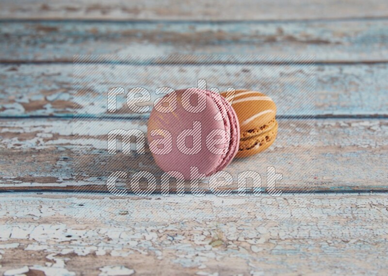 45º Shot of of two assorted Brown Irish Cream, and Purple Strawberry macarons  on light blue background