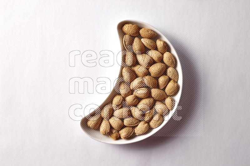 Almonds in a crescent pottery plate on white background