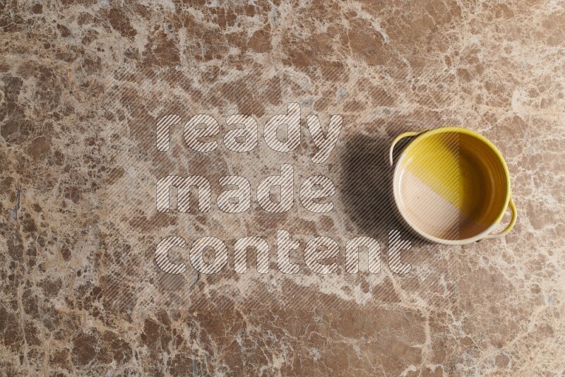 A multicolored pottery bowl on beige marble background
