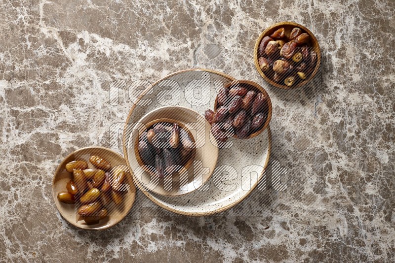 Dates in pottery plates and wooden bowls in a light setup