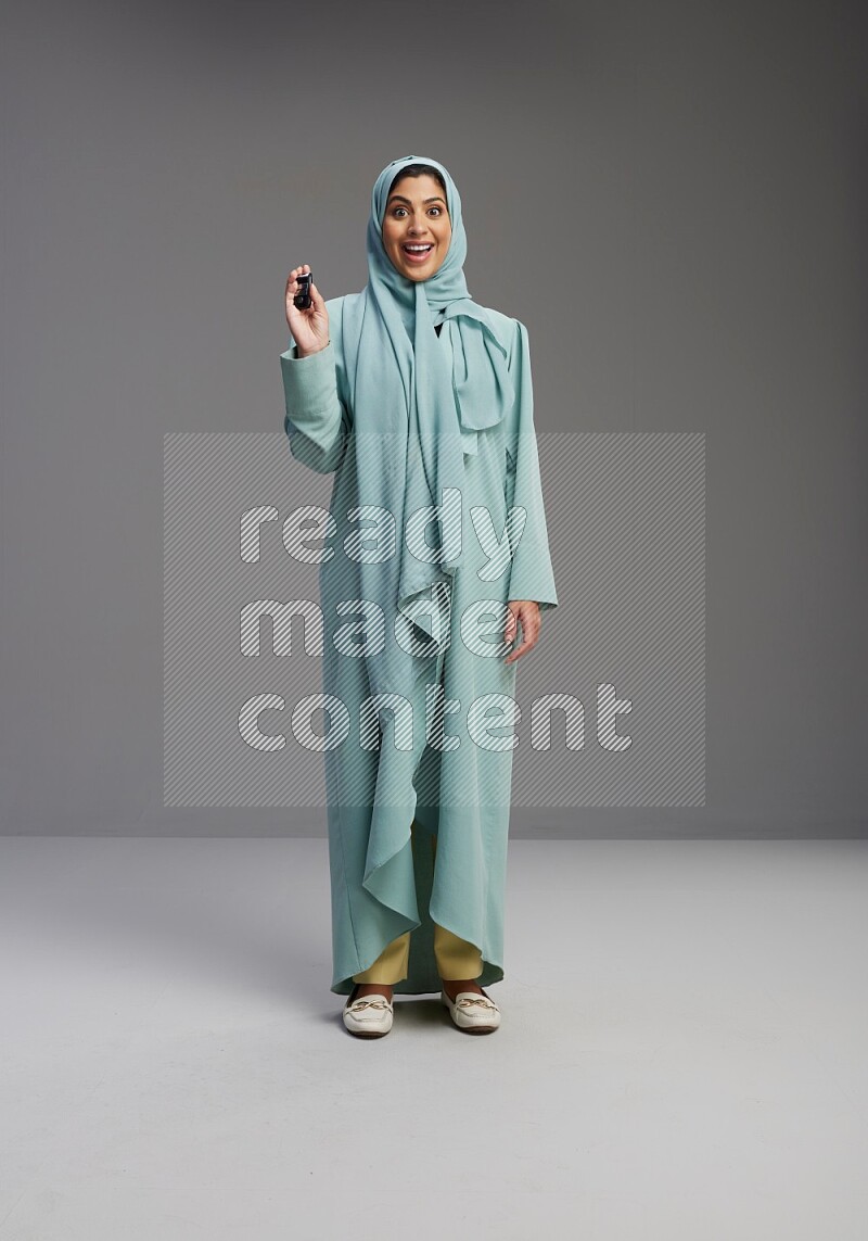 Saudi Woman wearing Abaya standing holding car key on Gray background