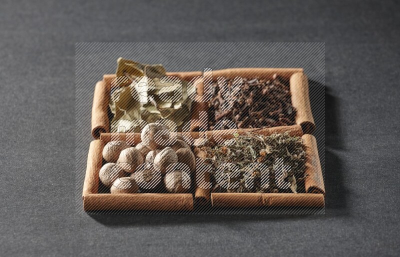 4 squares of cinnamon sticks full of bay laurel leaves, dried basil, cloves and nutmegs on black flooring