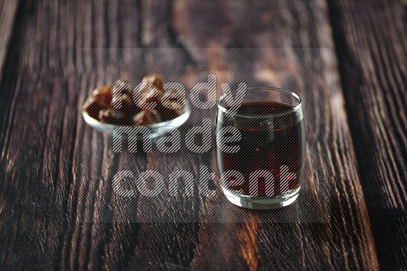 Cold drinks in a glass cup with dates such as water, tamarind, qamar eldin, sobia, milk and hibiscus on wooden background