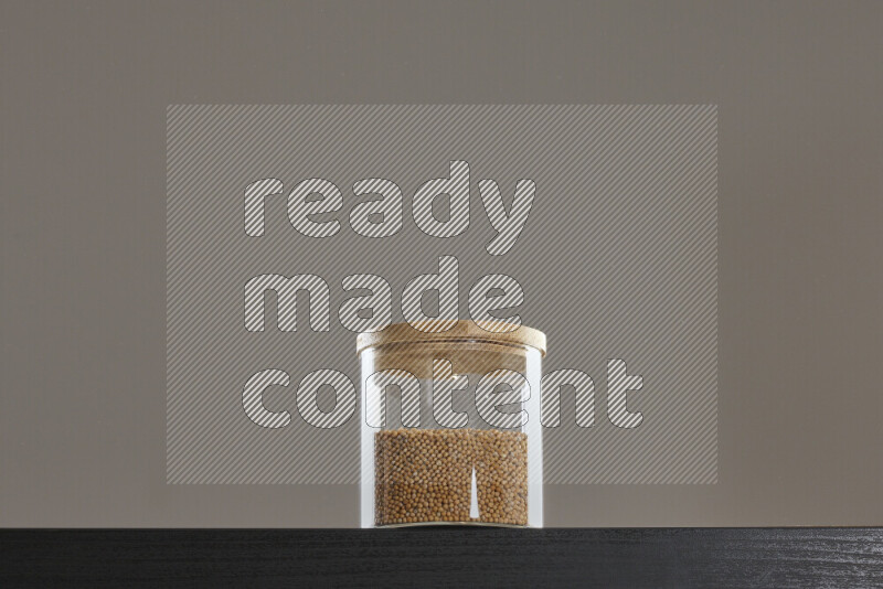 Mustard seeds in a glass jar on black background