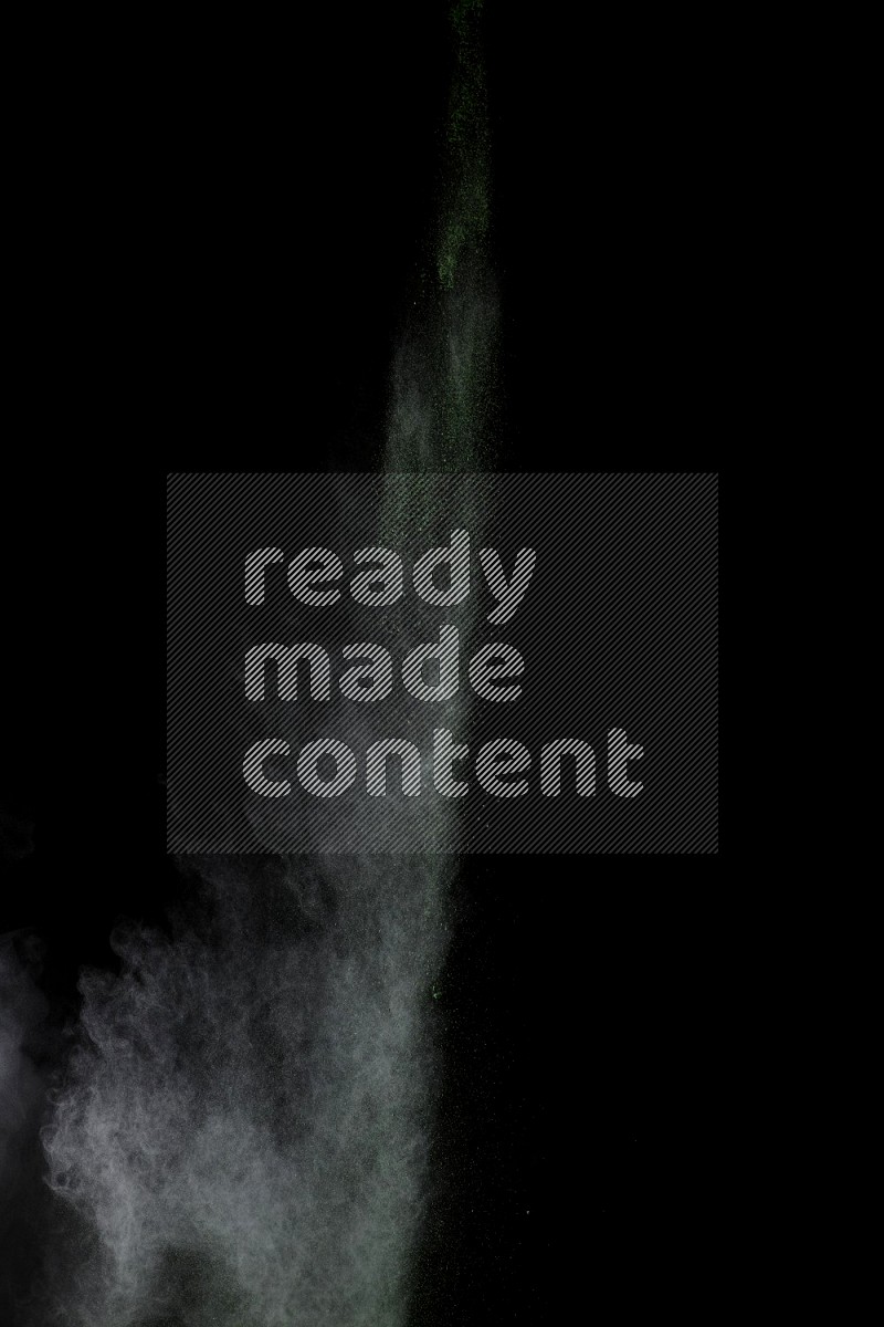 A side view of green powder explosion on black background