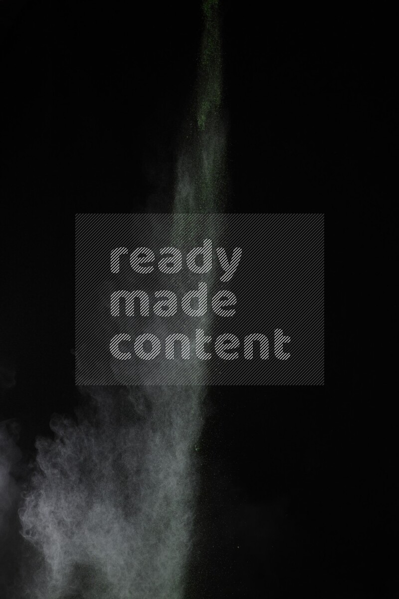 A side view of green powder explosion on black background
