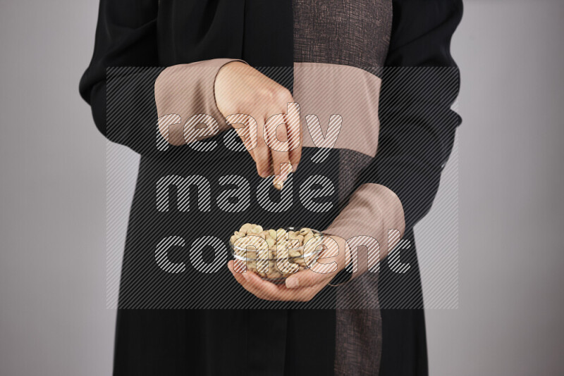 Woman in abaya holding different kinds of legumes in different positions