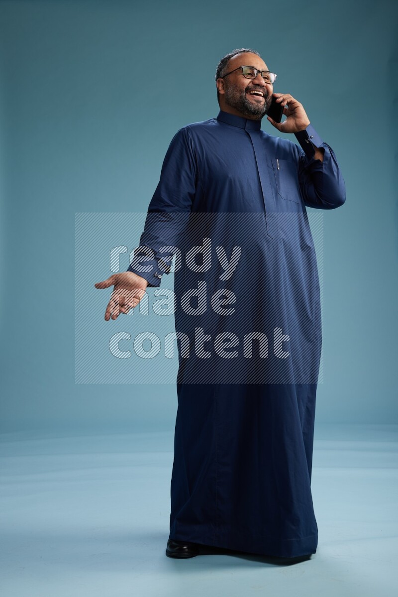 Saudi Man without shimag Standing talking on phone on blue background
