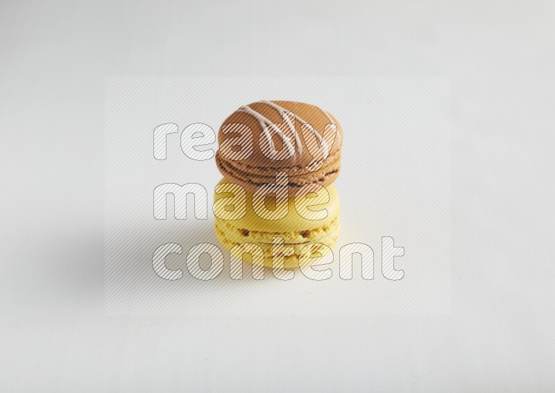 45º Shot of of two assorted Brown Irish Cream, and Yellow Lemon macarons on white background