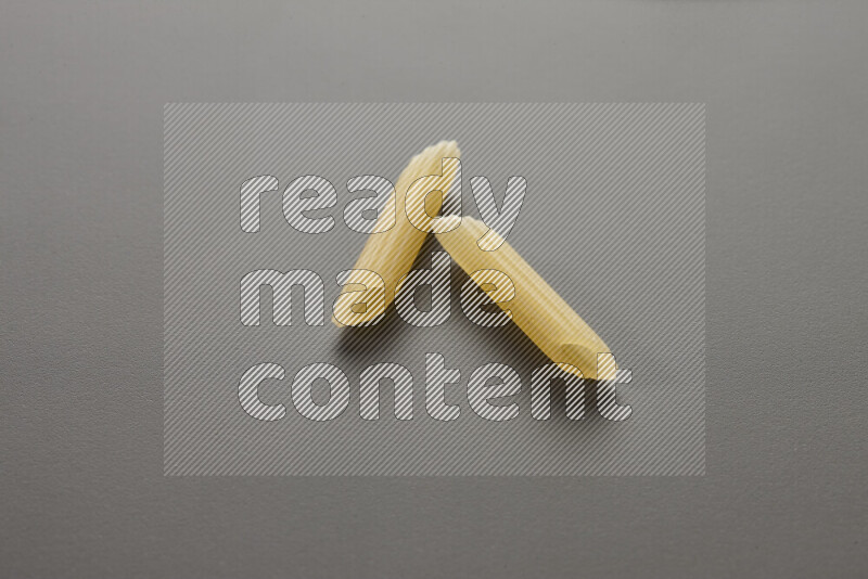 Mini penne pasta on grey background