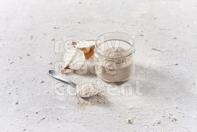 A glass jar full of onion powder on white background