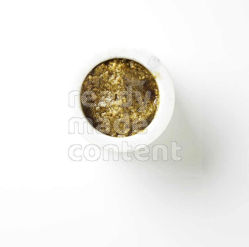small white ceramic round bowl filled with pesto paste on a white counter top