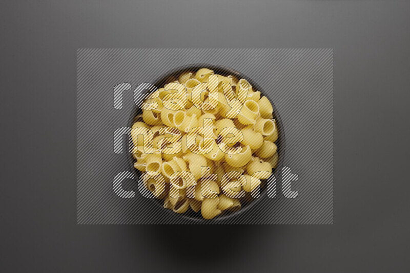 Pipe pasta in a pottery bowl on grey background