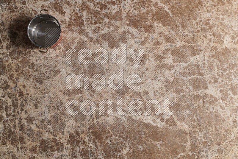 A small copper pot on beige marble background