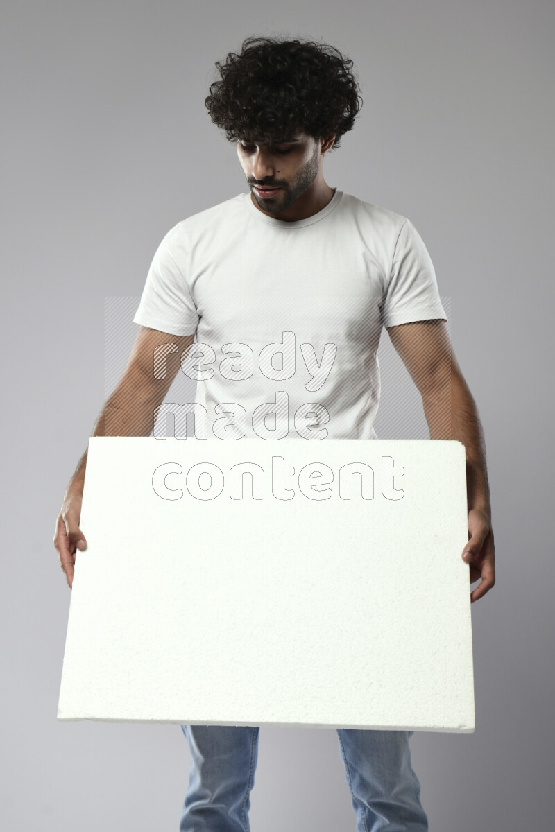 A man wearing casual standing and holding a white board on white background