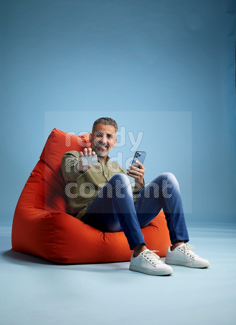 A man sitting on an orange beanbag and holding ATM card