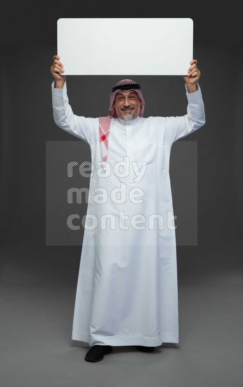 Saudi man with shomag Standing holding social media sing on gray background