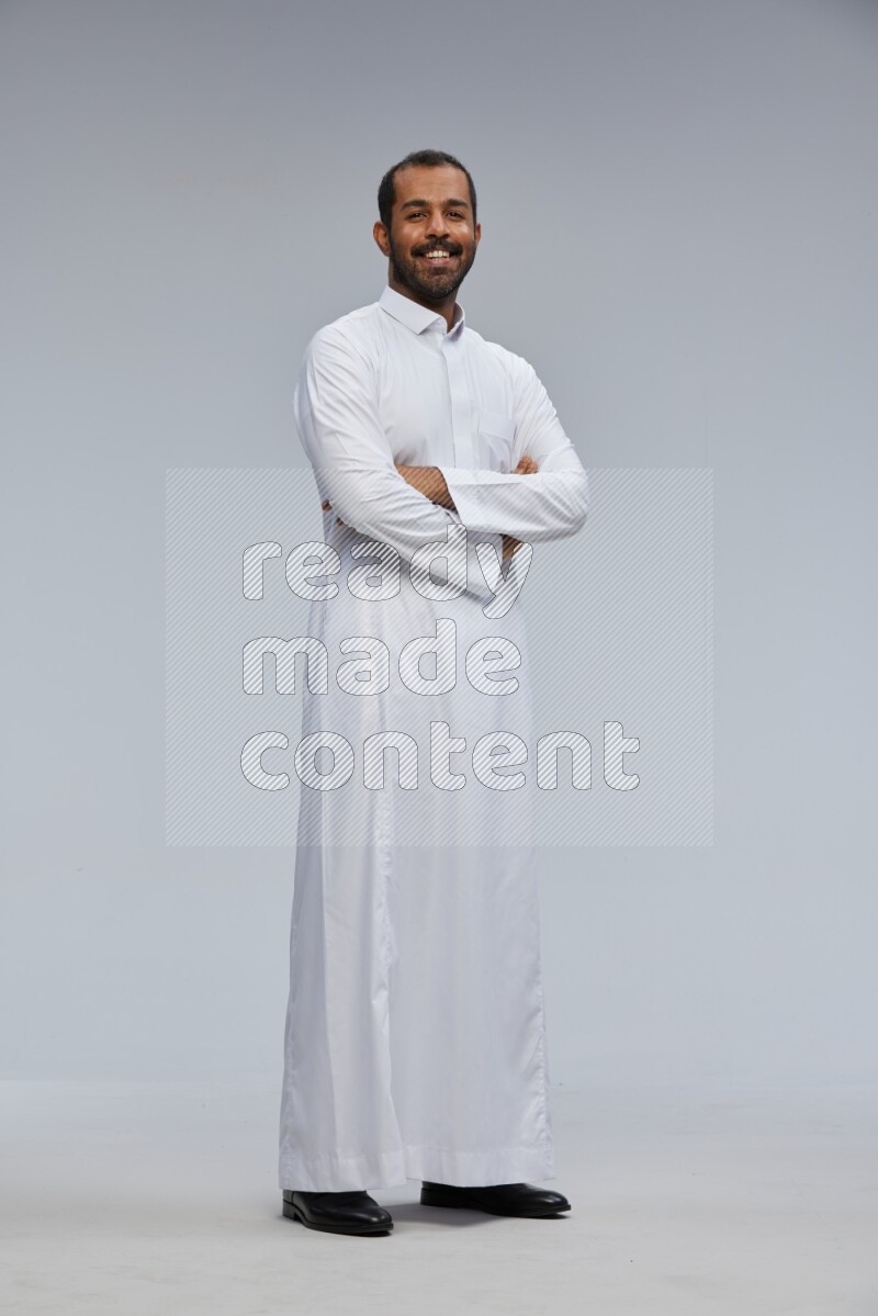 Saudi man wearing Thob standing with crossed arms on Gray background