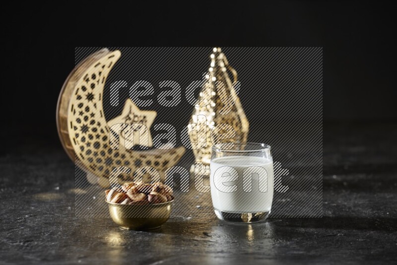 مكسرات في وعاء معدني مع الحليب بجانب فوانيس ذهبية علي خلفية سوداء