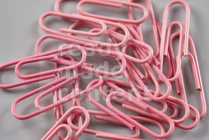 Pink paper clips isolated on a grey background