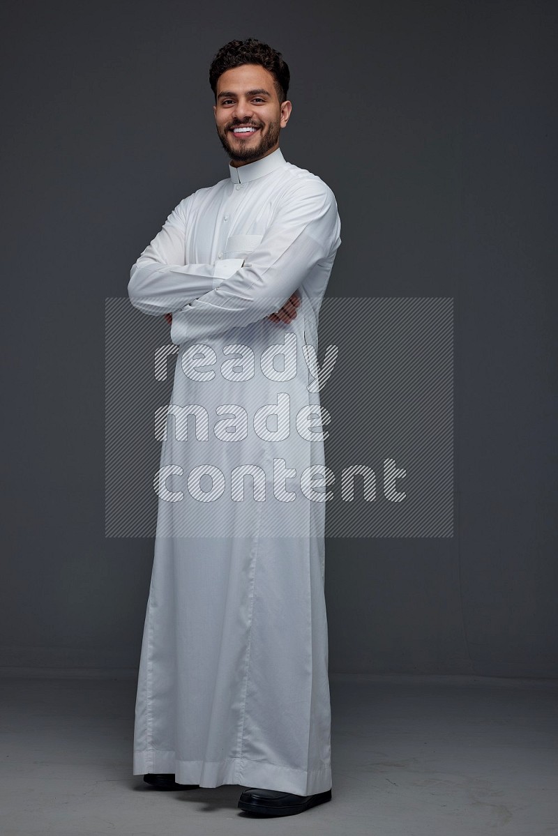 A Saudi man wearing Thobe standing and making different poses eye level on a gray background