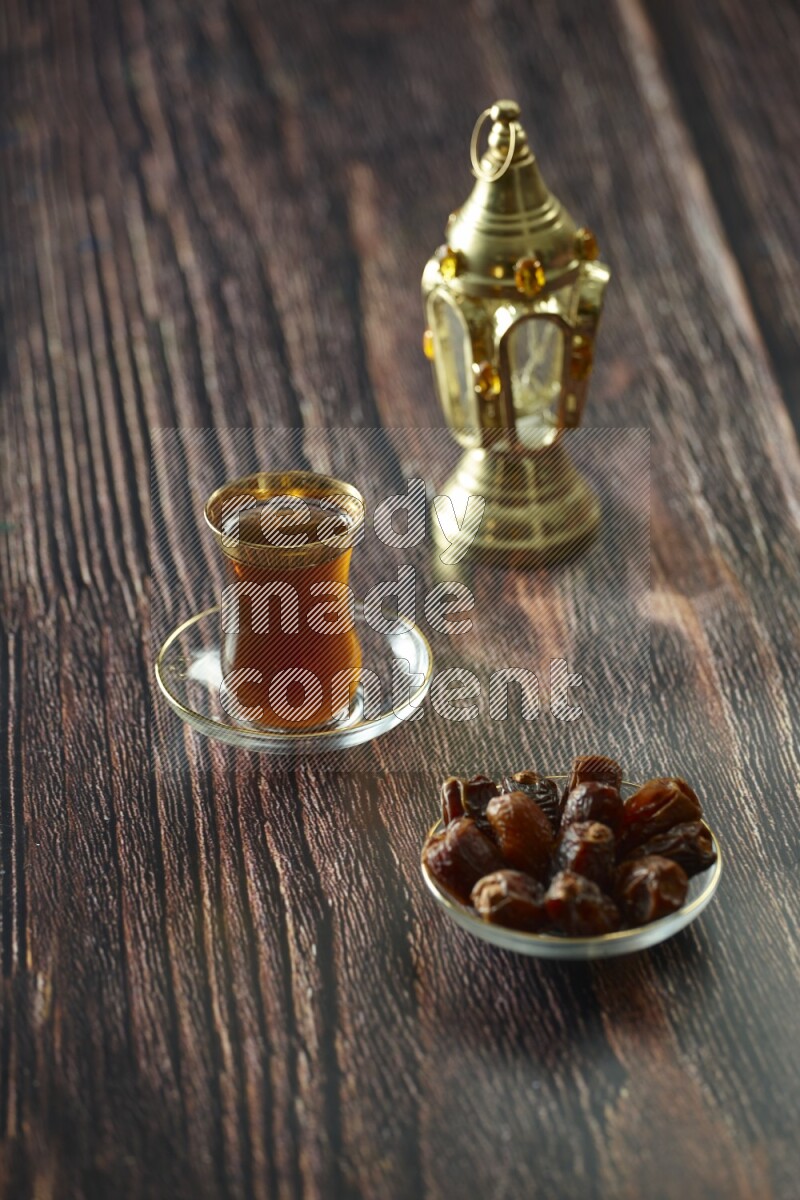 A golden lantern with different drinks, dates, nuts, prayer beads and quran on brown wooden background