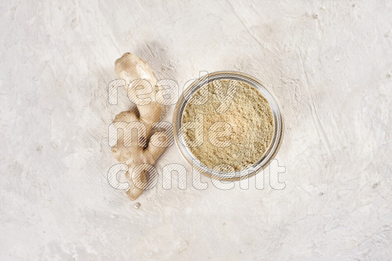 A glass bowl full of ground ginger powder on white background