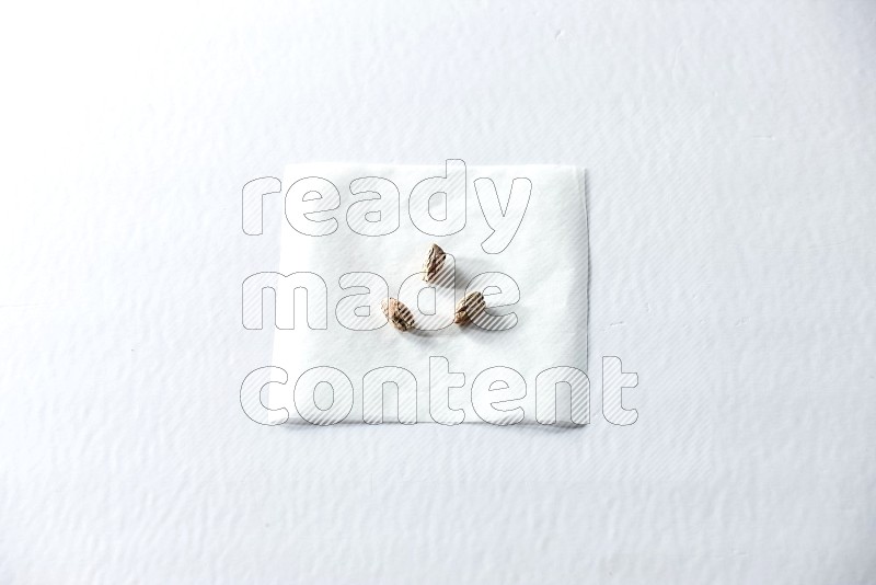 3 peeled pistachios on a piece of paper on a white background in different angles