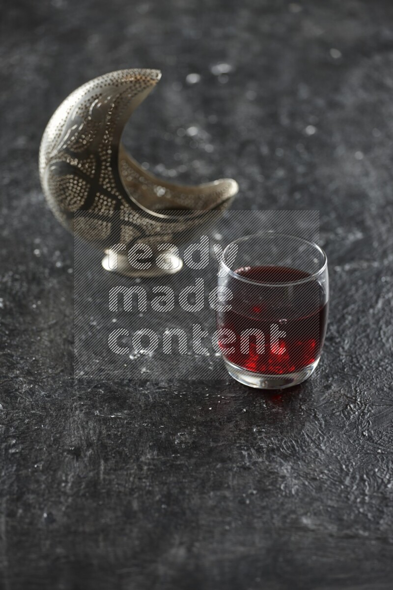 فانوس فضي مع مشروبات مختلفة وتمر ومكسرات وسبحة صلاة وقرآن على خلفية سوداء