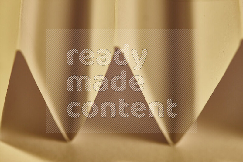 A close-up abstract image showing sharp geometric paper folds in warm gradients