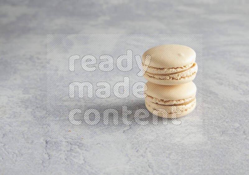 45º Shot of two white marbleCaramel fleur de sel macarons  on white  marble background