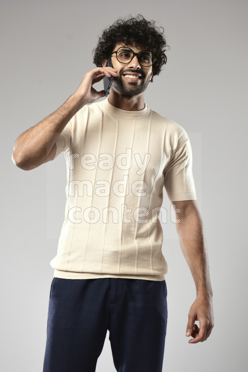 A man wearing casual standing and talking on the phone on white background
