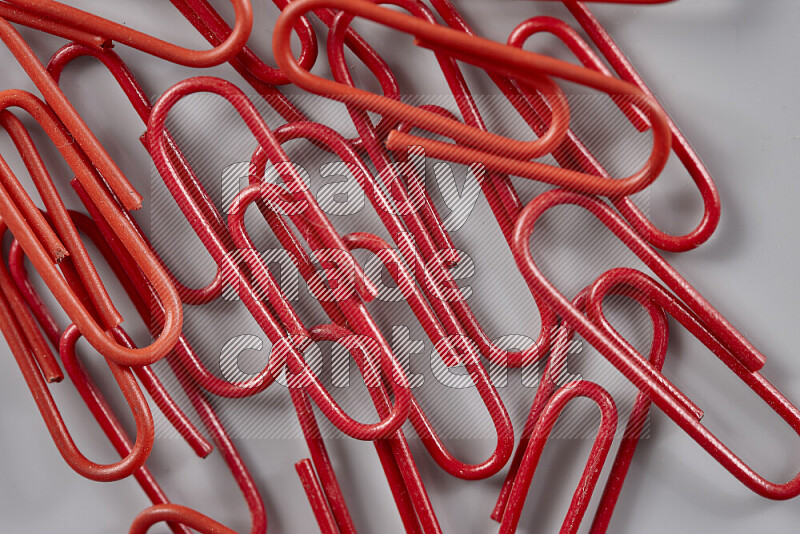 Red paper clips isolated on a grey background